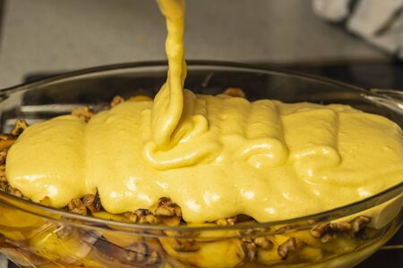 Cream added to the tray over the apples to prepare the apple cake.の写真素材