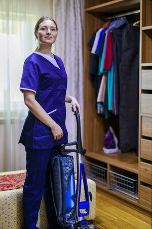 Young Female Maid Cleaning Floor With Vacuum Cleanerの写真素材