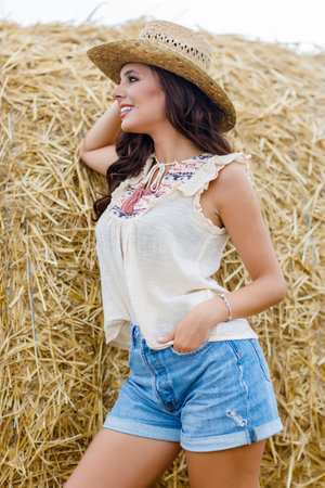 Beautiful cowboy woman Posing near at the haystacks, Fashion concept.
