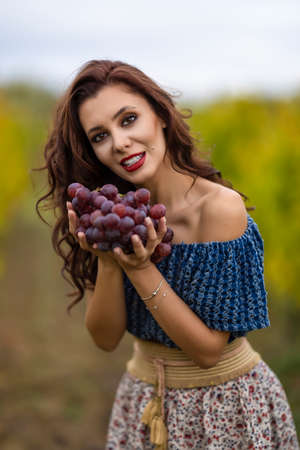 Beautiful Woman Holding Grapes In Her Hand In Vineyard.Autumn Seasonの写真素材