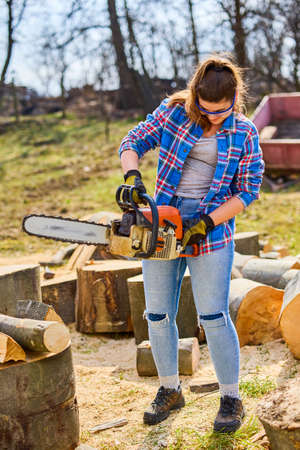 Young Woman using chainsaw to cut a log for firewood.の写真素材