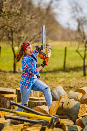 Young Woman using chainsaw to cut a log for firewood.の写真素材