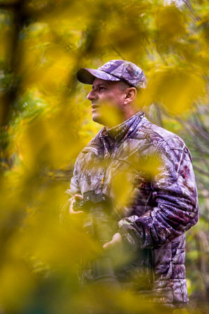 professional photographer in camouflage clothes working in nature. autumn day.の写真素材