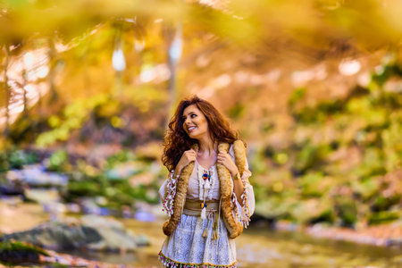 Autumn portrait with a beautiful woman in different positions near a mountain river in the autumn...