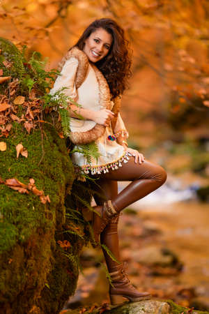 Autumn portrait with a beautiful woman in different positions near a mountain river in the autumn season.の写真素材