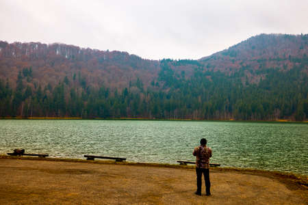 Tourist taking pictures of the landscape with St. Anne's Lake, Lake in Transylvania, Romaniaの写真素材