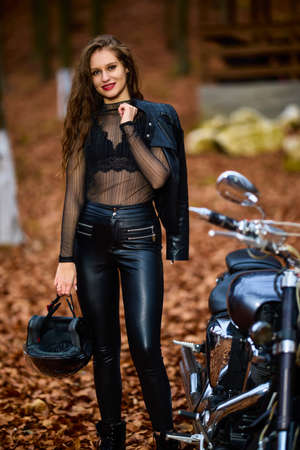 A beautiful woman with long hair on a chopper motorcycle in autumn landscape.の写真素材