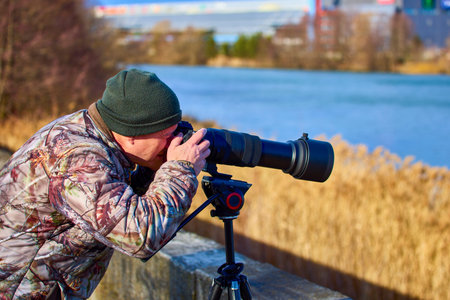 professional photographer in camouflage outfit is hidden in nature