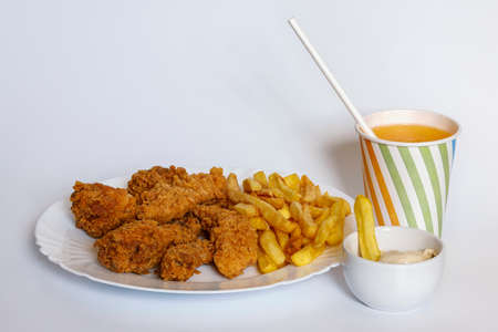 platter with hot wings, potatoes, sauce and orange juice on a white background.の写真素材