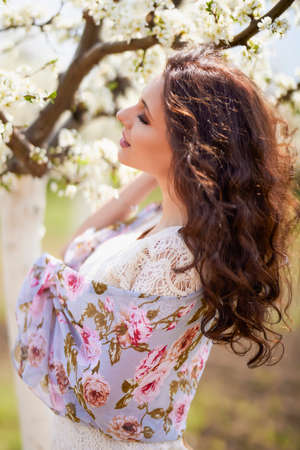 Portrait of a beautiful woman with long hair near flowering trees in spring.の写真素材