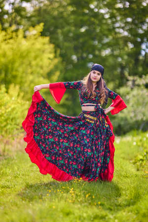 beautiful woman in traditional gypsy dress posing in nature in springの写真素材
