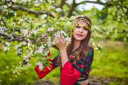 beautiful woman in traditional gypsy dress posing in nature in springの写真素材