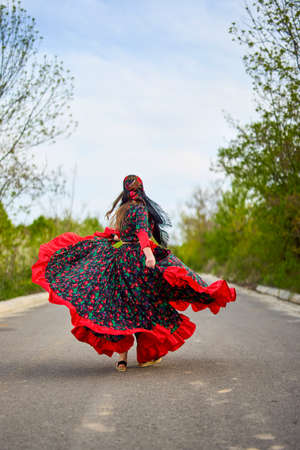 beautiful woman in traditional gypsy dress posing in nature in springの写真素材