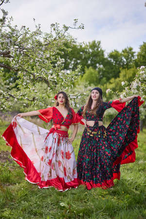 two dancers in traditional gypsy dresses dance in nature on a spring dayの写真素材
