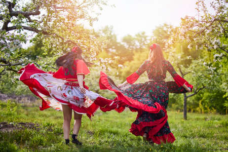 two dancers in traditional gypsy dresses dance in nature on a spring dayの写真素材