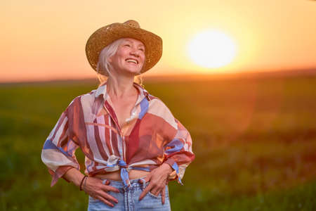 portrait of a middle-aged woman in the wheat field at sunsetの写真素材