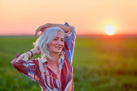 portrait of a middle-aged woman in the wheat field at sunsetの写真素材