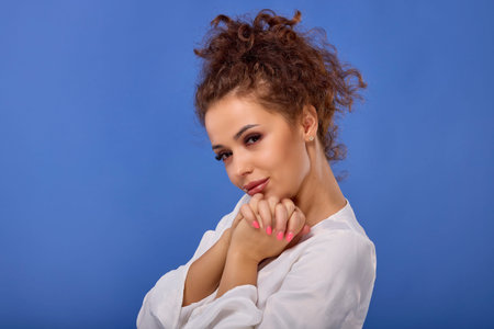 Portrait of a beautiful woman with curly hair on a blue backgroundの写真素材