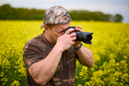 A professional photographer taking pictures of a flowering rapeseed field