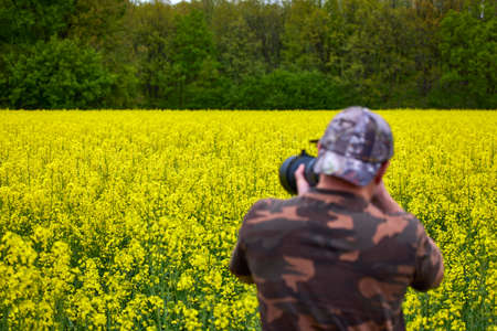 A professional photographer taking pictures of a flowering rapeseed fieldの写真素材