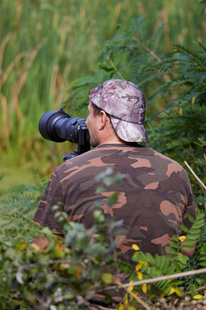 a professional photographer in camouflage clothing seen from behindの写真素材