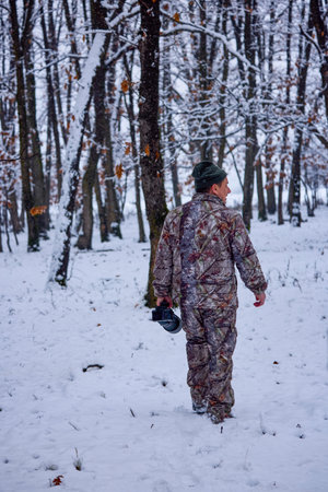 a male photographer in camouflage clothes in a winter landscapeの写真素材