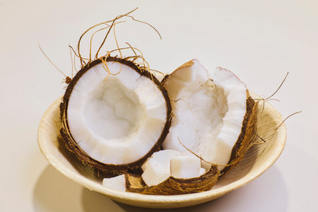 broken coconut in a bamboo plate on a table