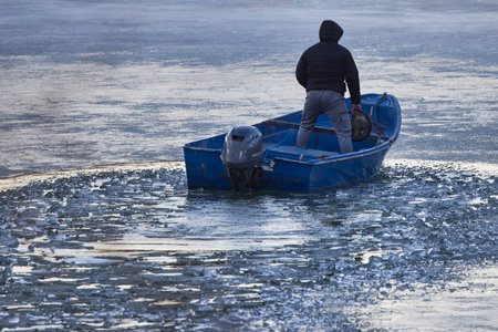 a man in a boat on a frozen riverの写真素材