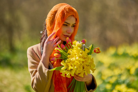 Portrait of a beautiful woman in a garden with yellow snowdrops on a spring day.の写真素材