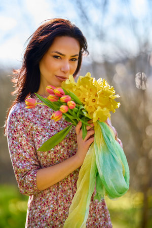 Portrait of a beautiful woman in a garden with yellow snowdrops on a spring day.の写真素材