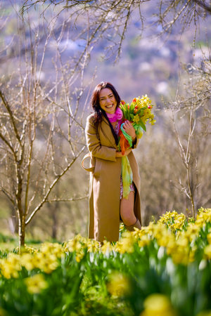Portrait of a beautiful woman in a garden with yellow snowdrops on a spring day.の写真素材