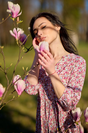 portrait of a beautiful woman posing with a magnolia on a sunny spring day.の写真素材