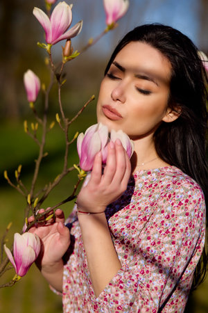 portrait of a beautiful woman posing with a magnolia on a sunny spring day.の写真素材