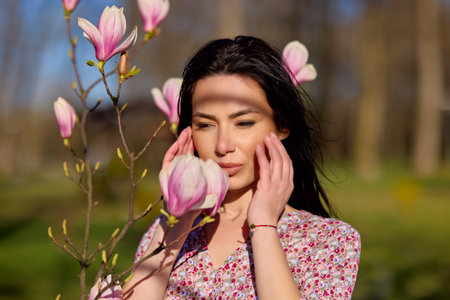 portrait of a beautiful woman posing with a magnolia on a sunny spring day.の写真素材