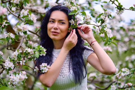 portrait of a beautiful brunette woman in a blossoming apple orchardの写真素材