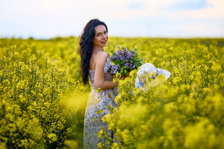 portrait of a brunette woman in a rapeseed field in spring