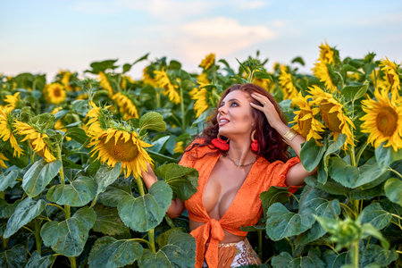portrait of a beautiful woman near a field of sunflowers on a sunny day at sunset.の写真素材