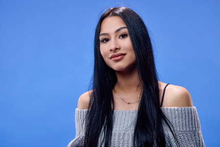 Portrait of the beautiful young brunette posing in the studio on a blue background