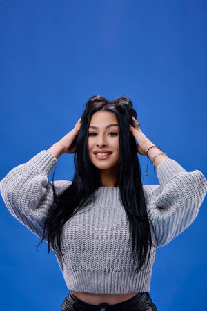 Portrait of the beautiful young brunette posing in the studio on a blue background
