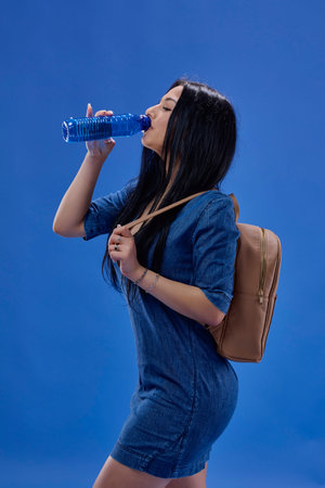a young brunette with long hair posing in the studio with a backpack, Back to school concept.の写真素材
