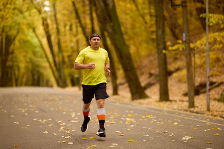 Portrait of a middle-aged man running in the park on an autumn day.の写真素材