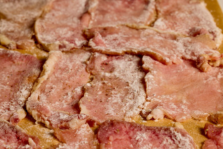 Pork tenderloin thinly sliced and prepared for schnitzel before cooking.