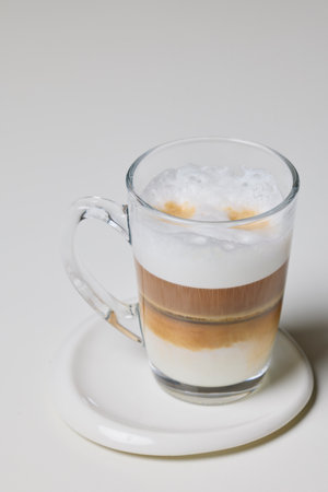 a transparent mug with Cappuccino on a table.の写真素材