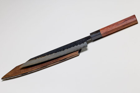 Professional kitchen knife next to a wooden sheath