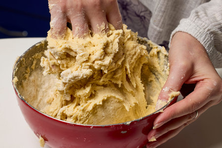 The hands of a woman preparing a traditional homemade dough cake in the kitchen.