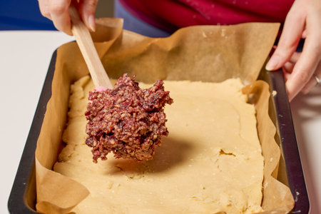 The hands of a woman preparing a traditional homemade dough cake in the kitchen.の写真素材