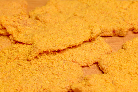 chicken cutlets on a wooden counter ready to be cooked.
