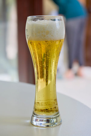 a glass of beer on a table in the blurred background.