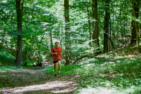 a strong middle-aged man running through the forestの写真素材