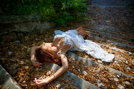 Portrait of a beautiful woman in a white dress on the stairs, artistic photography.の写真素材